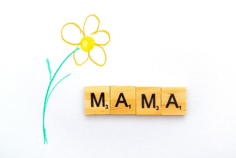 gezeichnete Blume und das Wort Mama aus Scrablesteinen