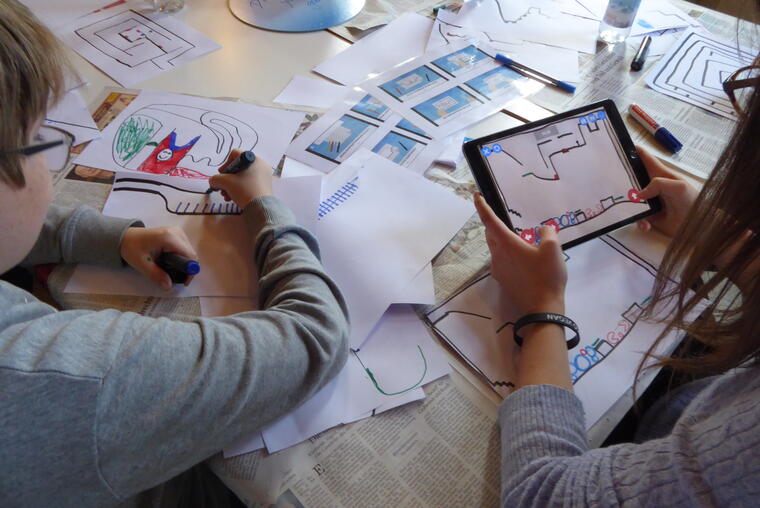 Zwei Kinder scannen Zeichnungen mit ipads in eine Spiele_App ein